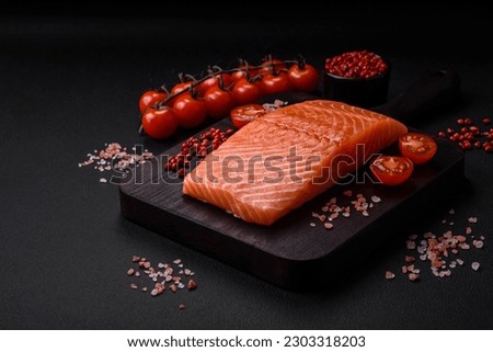 Fresh raw salmon red fish fillet with salt and spices on a dark concrete background