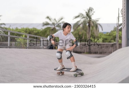 asian child skater or kid girl playing skateboard or ride surf skate up to wave ramp or wave bank to fun bottom turn surfskate in skate park by extreme sport surfing to wears knee pads for body safety Royalty-Free Stock Photo #2303326415