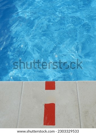 End of the swimming pool with blue fresh water in outside yard of residential area in Madrid, Spain. Vertical photo.
