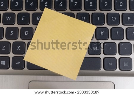 top view of blank yellow note on laptop keyboard