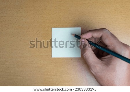 man hand using pencil writing on blank note on wooden desk