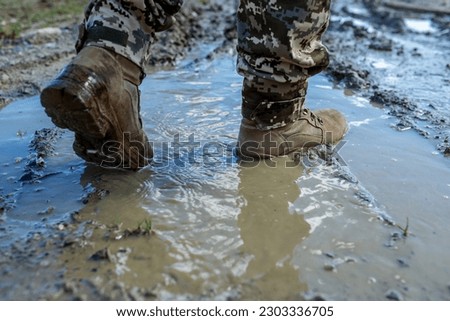 Brown military boots on mud and puddle. Armed Forces of Ukraine. Ukrainian soldier. Royalty-Free Stock Photo #2303336705