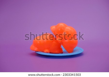 Pumpkin toy that can be split then put back together. toy pumpkin and knife isolated purple background. toy pumpkin on a blue plate.