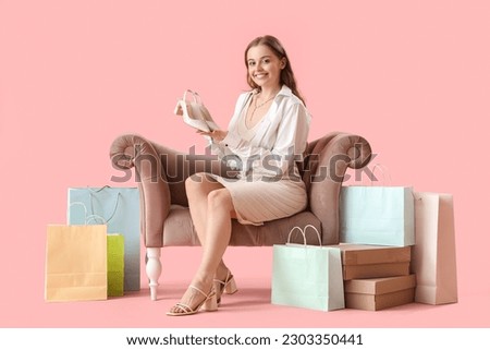 Young woman with stylish shoes in armchair on pink background Royalty-Free Stock Photo #2303350441