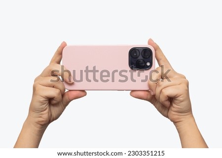 Mobile phone with photo camera in a pink case in female hands isolated on a white background. Blank with an empty copy space for the design. Mockup of a smartphone. Young woman takes picture