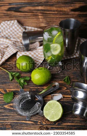 Glass of cold mojito and ingredients on wooden background