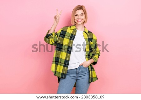Photo portrait of pretty young girl showing v-sign hello shopping model wear plaid yellow garment isolated on pink color background