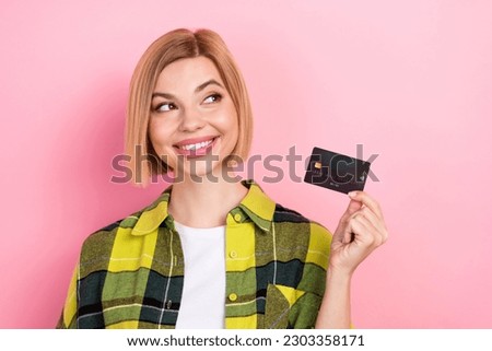 Photo portrait of lovely young lady look empty space credit card dressed stylish checkered yellow clothes isolated on pink color background