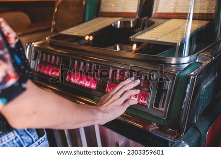 Vintage American music jukebox with illuminated buttons, process of choosing song composition, retro old-fashioned juke-box with vinyl discs musical box machine in cafe diner restaurant Royalty-Free Stock Photo #2303359601