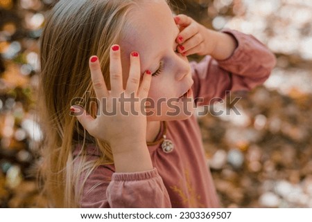 Little girl with nail polish pushing hair out of face