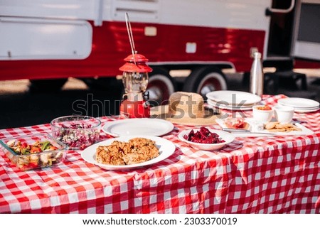 Feast on a Red and White Table by an RV for Gourmet Camping and Meals