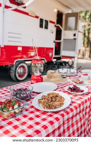 Delicious Meal Outside a Red and White RV with Lantern at a Campground