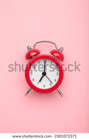 Red vintage alarm clock on pink background. Space for text. Vertical photo