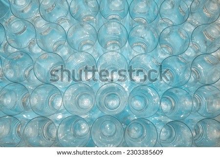 A top view shot of several glasses arranged nicely and neatly. The glasses are all clean and clear, and they reflect the light in a beautiful way.