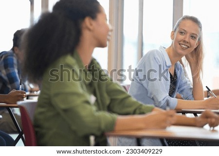Smiling university students talking in classroom