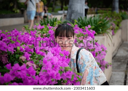Asian women Taking a picture with pink bougainvillea, this picture was taken at Benjakitti Park, Asoke area, Bangkok, Thailand.