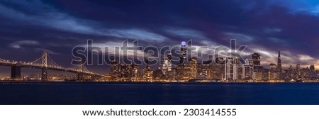 A panorama picture of the Oakland Bay Bridge and Downtown San Francisco as seen from Treasure Island at sunset.