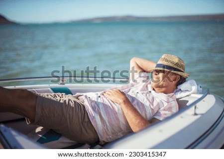 Older man relaxing in boat on water Royalty-Free Stock Photo #2303415347