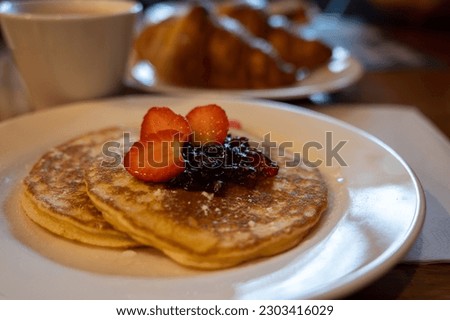 Breakfast with homemade American pancakes served with strawberry jam and fresh ripe strawberries, coffee and croissants