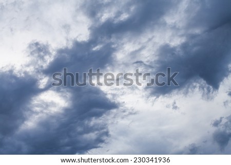 Ominous dark grey and blue wispy fractus storm clouds during a high wind contrasted against a lighter color sky