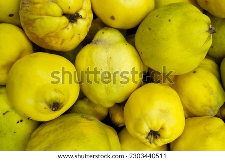 Close-up on a stack of quinces for sale a market stall.