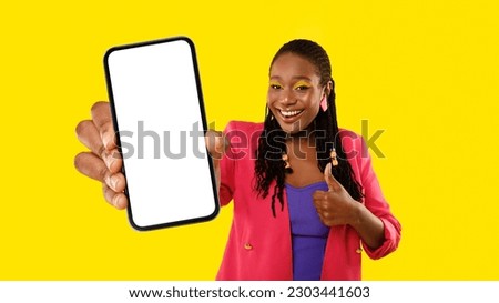 Mobile Offer Approval. Cheerful African American Lady Showing Cellphone With Large Blank Screen And Gesturing Thumbs Up Posing Over Yellow Studio Background. Panorama, Mockup Royalty-Free Stock Photo #2303441603