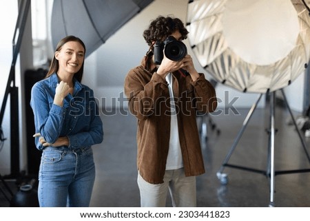 Capturing the moment. Male photographer with his trusty assistant doing photo shoot in studio. Photographer taking a photograph with studio flash light on.