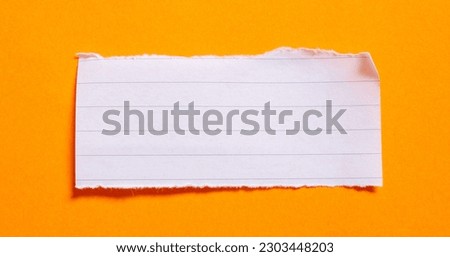 Ripped lined notebook paper on orange background with copy space.