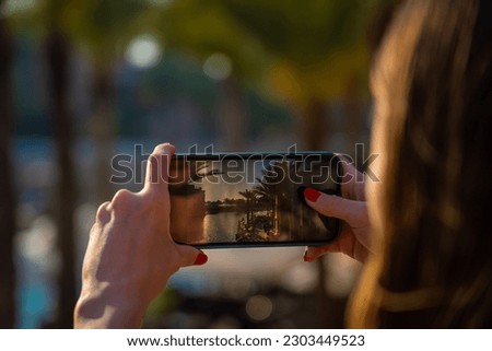 A young woman takes a picture of the Dubai Waterfront Promenade with her mobile phone.
