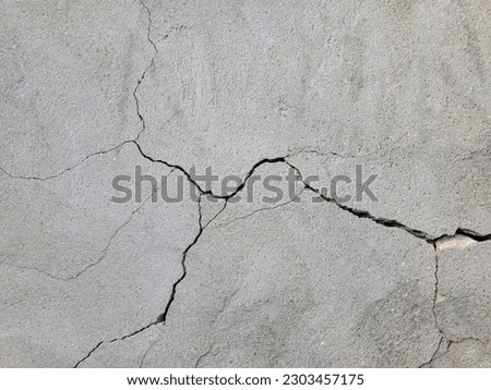 Cracked concrete wall covered with gray cement mortar. Destruction caused by an earthquake. Large uneven crack in the wall. Copy space. Texture background. Repair, construction of buildings, shrinkage Royalty-Free Stock Photo #2303457175