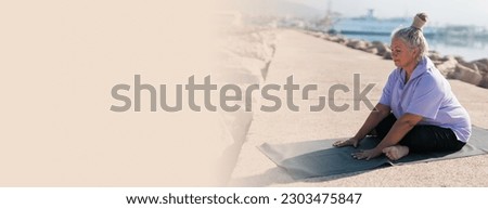 Banner Senior woman with dreadlocks in stretching position by the sea at morning copy space. Elderly woman doing yoga near beach.