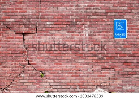 Handicapped parking sign on cracked brick wall