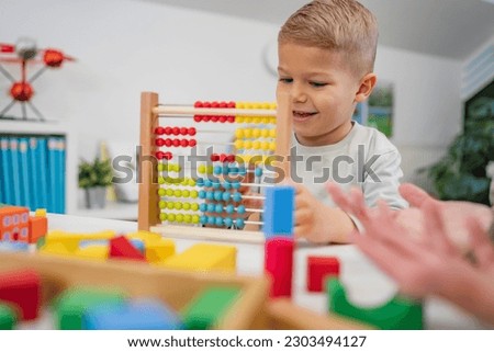 Cheerful children playing with colorful didactic toys in a Kindergarten.  Play with educational toys. Learning through play. Royalty-Free Stock Photo #2303494127