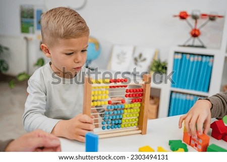 Cheerful children playing with colorful didactic toys in a Kindergarten.  Play with educational toys. Learning through play. Royalty-Free Stock Photo #2303494131