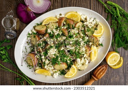 Greek Potato Salad with Feta Cheese, Fresh Herbs, and Lemon Wedges: Baby red potatoes topped with feta, dill, capers, and extra virgin olive oil Royalty-Free Stock Photo #2303512321