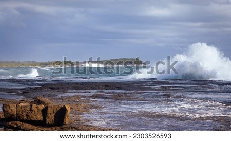 Wave breaking along edge of a wave cut platform on the east coast of Australia during stormy conditions Royalty-Free Stock Photo #2303526593
