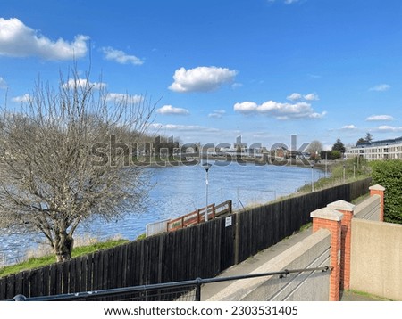 Nature picture with a view of river or lake and bridge in a garden or park in the morning sunset or sunrise. flowers and pavement and fishing in England