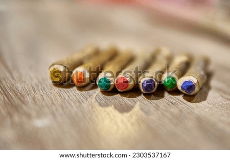 HANDMADE RUSTIC COLORED CRAYONS PENCIL OVER A WOODEN TABLE. MADE OF NATURAL WOOD TRUNK. Selective focus, blurred background. Copy space