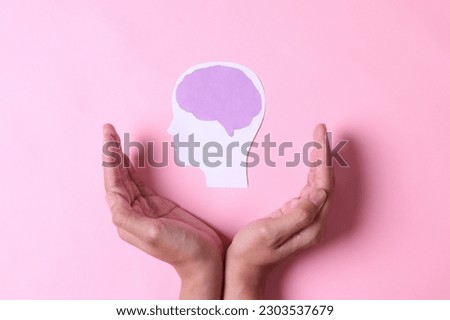 Hands with brain paper cutout isolated on pink background. World mental health day.  Royalty-Free Stock Photo #2303537679