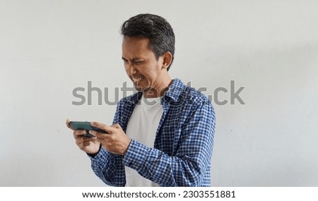 Asian man playing video game on smartphone