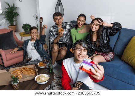 latin LGBT friends taking photo selfie with mobile phone and having fun at home in Mexico, Hispanic homosexual and lgbtq community in Latin America Royalty-Free Stock Photo #2303563795