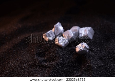 Pure silver or platinum or rare earth from the mine that was placed on the black sand Royalty-Free Stock Photo #2303568755