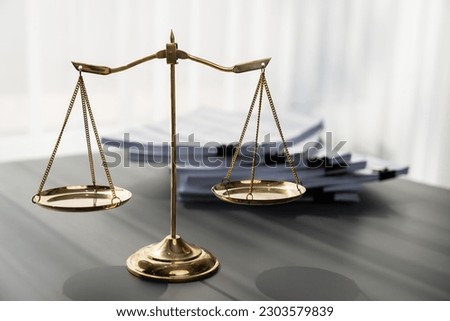 Shiny golden balanced scale and pile of legal paper on desk in lawyer office as concept justice and legal symbol. Scale balance for righteous and equality judgment by lawyer and attorney. equility