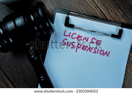 Concept of License Suspension write on paperwork with gavel isolated on Wooden Table. Royalty-Free Stock Photo #2303584053