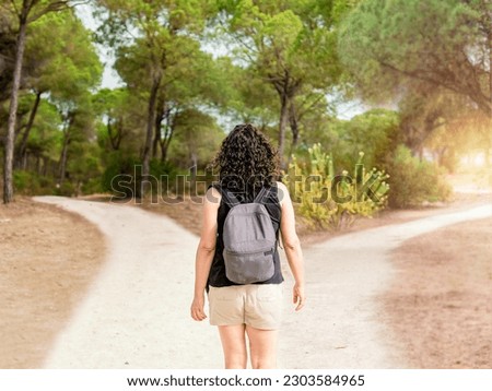 Woman choosing to take a light path or a dark path in a forest. Concept of decision making in life. Royalty-Free Stock Photo #2303584965
