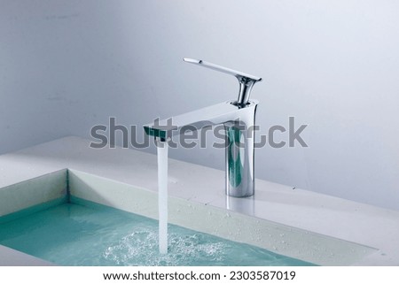 Modern Domestic Bathroom with Faucets. A domestic bathroom featuring a sink, faucet, and bathtub surrounded by household equipment. Water Tap. Royalty-Free Stock Photo #2303587019