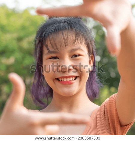 Happy teen girl 11-15 year old. Portrait of beautiful woman smiling with perfect smile at park during sunset. Smile face asian lady girl wear casual cloth, making frame gesture.