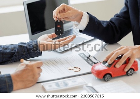 Closing sale. Asian customer signing car insurance paperwork or lease contract or agreement. Buy or sell a new or used car with car keys on the table.