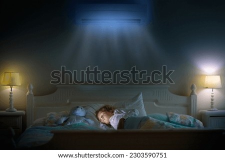 Air conditioner in bedroom. Kids room climate control. Mother and child in bed under cool air breeze. Comfortable temperature for healthy sleep on summer night. Air conditioning device in family home. Royalty-Free Stock Photo #2303590751
