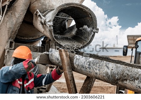 Mixer truck is transport concrete to the casting place on building site. Concrete is flowing into the foundations of the building. The worker directs the concrete to the place of pouring Royalty-Free Stock Photo #2303606221